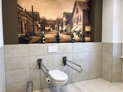 Barrierefreie WC-Anlage Museum Harsefeld Sanitärraum mit barrierefreier Toilette inklusive Haltegriffe und Notfall-Zugschnur. Im Hintergrund an der Wand ein historisches Bild von der Markstraße Harsefeld © LEADER-Regionalmanagement