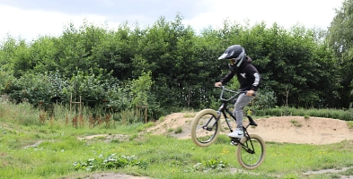 Biker mit Helm, der auf unebenem Gelände mit dem Mountainbike springt.