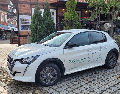 Ein Dorfstromer-Fahrzeug steht vor einem Gebäude im Harsefelder Ortskern&nbsp;&copy;&nbsp;Samtgemeinde Harsefeld