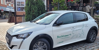 Ein Dorfstromer-Fahrzeug steht vor einem Gebäude im Harsefelder Ortskern