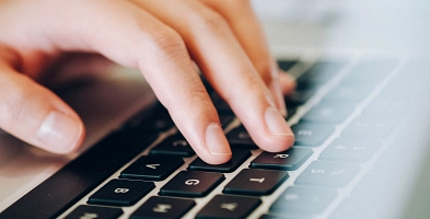 menschliche Hände an einer Laptoptastatur