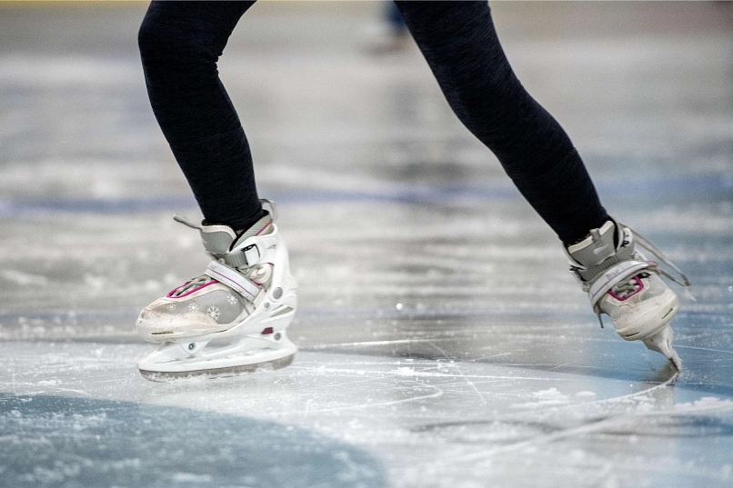 Weiße Schlittschuhe die eine Kurve auf dem Eis drehen.