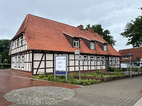 FIZ Front.jpg Auf dem Bild ist der Vordereingang des Familien-Informations-Zentrums zu sehen. Es gibt eine Rampe, die links an der Hauswand zum Eingang führt.
Im Vordergrund ist der Wegweiser zu sehen, auf dem die Eingänge zum FIZ, zum Stadtmarketing und zur Jugendkustschule angezeichnet sind. Im Hintergrund sieht man den Schaukasten mit aktuellen Informationen und Angeboten im FIZ. © Samtgemeinde Harsefeld