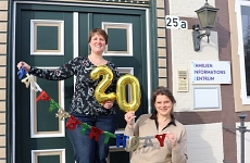 Frau Gerken und Frau Strasdas stehen vor dme FIZ Eingang und halten eine 20 hoch