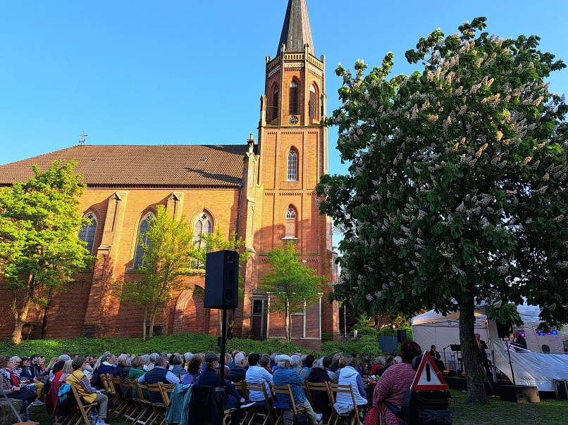 Klassik Open Air Seitlicher Blick auf die Kirche aus der Klosterpark-Ruine mit Besucher:innen des Klassik Open Airs © Stadtmarketing Harsefeld