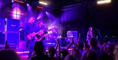 Zwei Männer mit Gitarren auf einer Bühne, davor jubelnde Menschen.