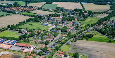 Zu sehen ist ein Schrägluftbild der Gemeinde Bargstedt mit Straßen, Wäldern, Äckern und Siedlungen.