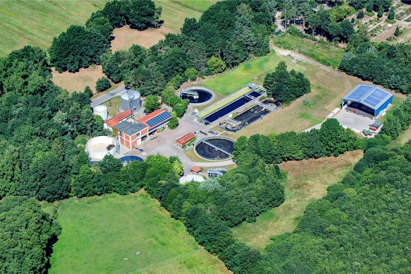 Ein Drohnenbild der Kläranlage Harsefeld, auf dem die Klärbecken, der Faulturm und die Trocknungshalle zu sehen sind. Zum Teil ist auch der angrenzende Friedhof sichtbar.