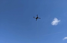 Am Himmel fliegender Hubschrauber mit herabhängender Messsonde.