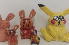drei größere und zwei kleinere getöpferte Osterhasen, teilweise angemalt, vor einer weißen Wand