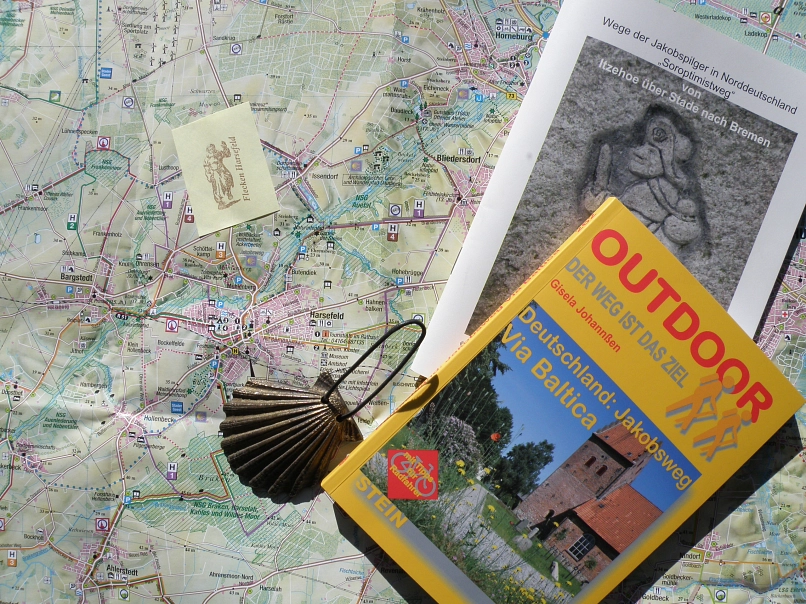 Pilgermaterialien, Jakobsmuschel Landkarte mit darauf abgelegtem Wanderbuch, Pilgerflyer, einem Pilgerstempel und einer Jakobsmuschel © Samtgemeinde Harsefeld