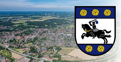 Luftbild von Harsefeld mit sichtbarer Umgehungsstraße im Vordergrund. Rechts ist das Wappen der Samtgemeinde Harsefeld zu sehen.