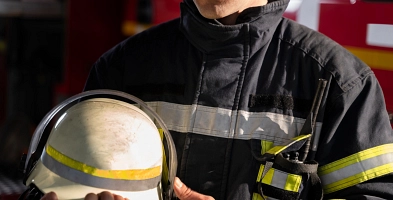 Ein Feuerwehrmann hält einen Helm in seinem Arm.
