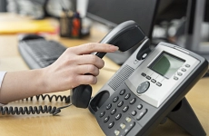 Eine Damenhand greift nach einem Telefonhörer