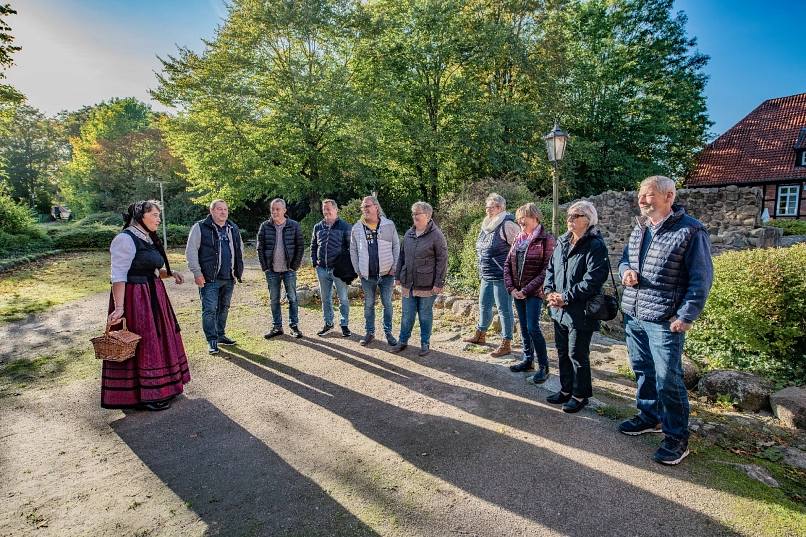 Gästeführerin in Geesttracht vor Gruppe von zuhörenden Menschen